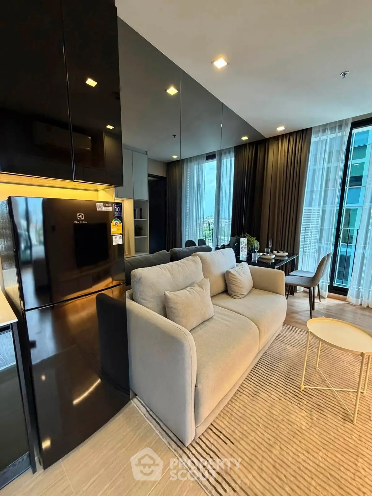 Modern living room with sleek design, featuring a cozy sofa, dining area, and large windows with city view.