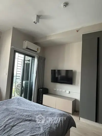 Modern bedroom with balcony access and wall-mounted TV in stylish apartment.