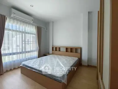 Spacious bedroom with large window and modern furnishings in a bright apartment.