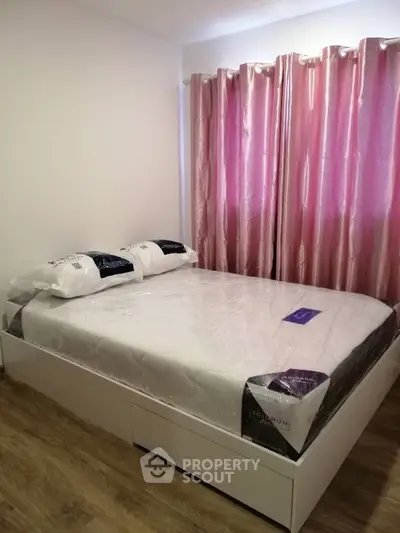 Cozy bedroom with elegant pink curtains and a neatly made bed, perfect for relaxation.