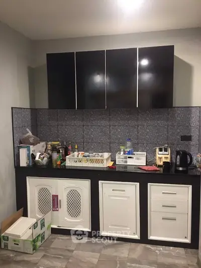 Modern kitchen with sleek black and white cabinetry and tiled backsplash.