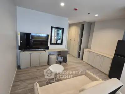 Modern living room with sleek design, featuring a large TV, comfortable seating, and stylish cabinetry.