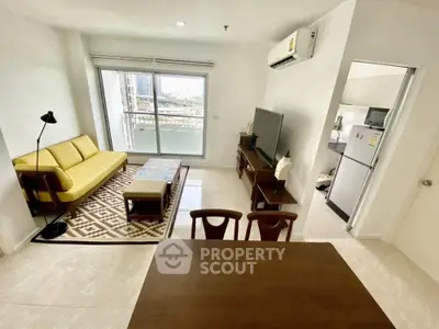 Modern living room with yellow sofa, TV, and dining area in open layout apartment.