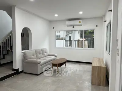 Spacious living room with modern sofa and natural light, perfect for relaxation and entertainment.