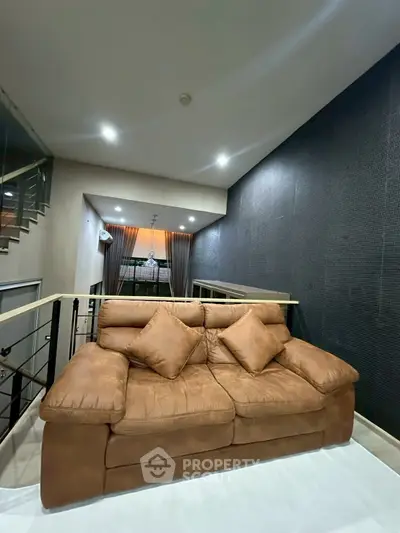 Spacious living room with plush brown sofa and modern lighting, perfect for relaxation and entertainment.