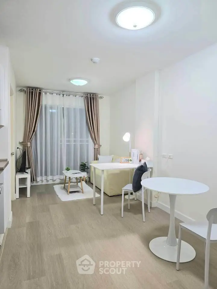 Modern living room with stylish decor and natural light, featuring a cozy seating area and elegant curtains.