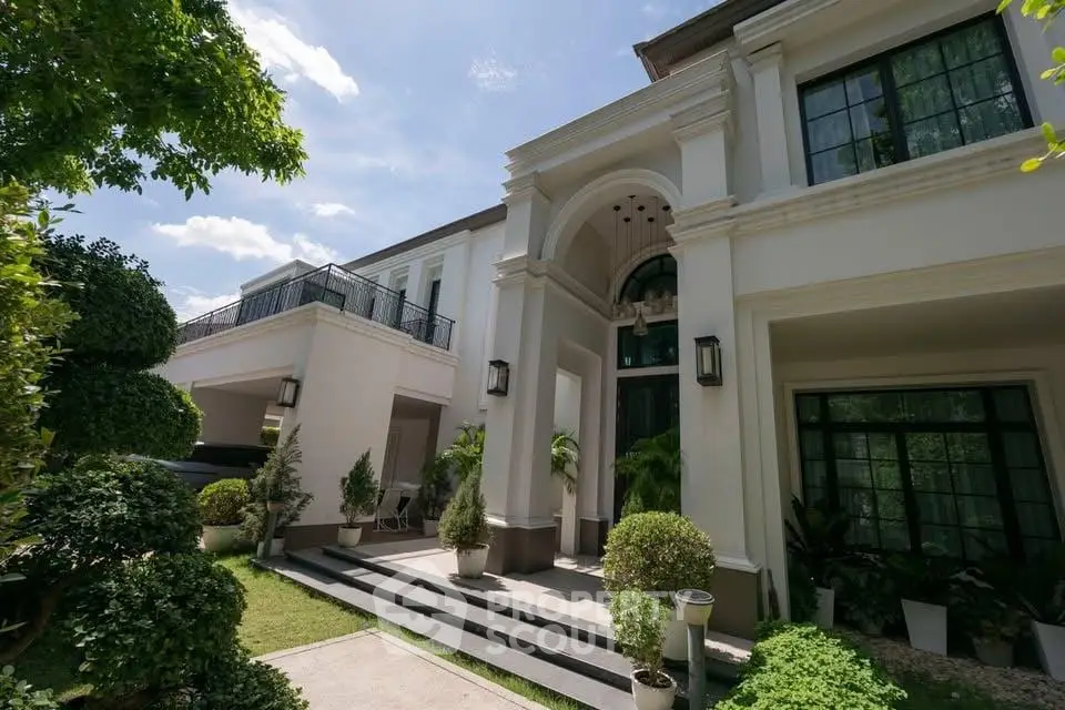 Luxurious two-story home with elegant entrance and lush garden, perfect for upscale living.