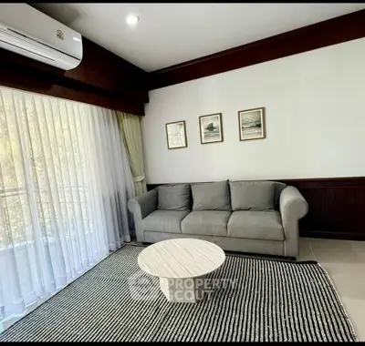Elegant living room with gray sofa, modern coffee table, and large window with sheer curtains.