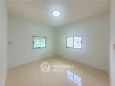 Spacious empty room with tiled floor and two windows, ideal for customization.