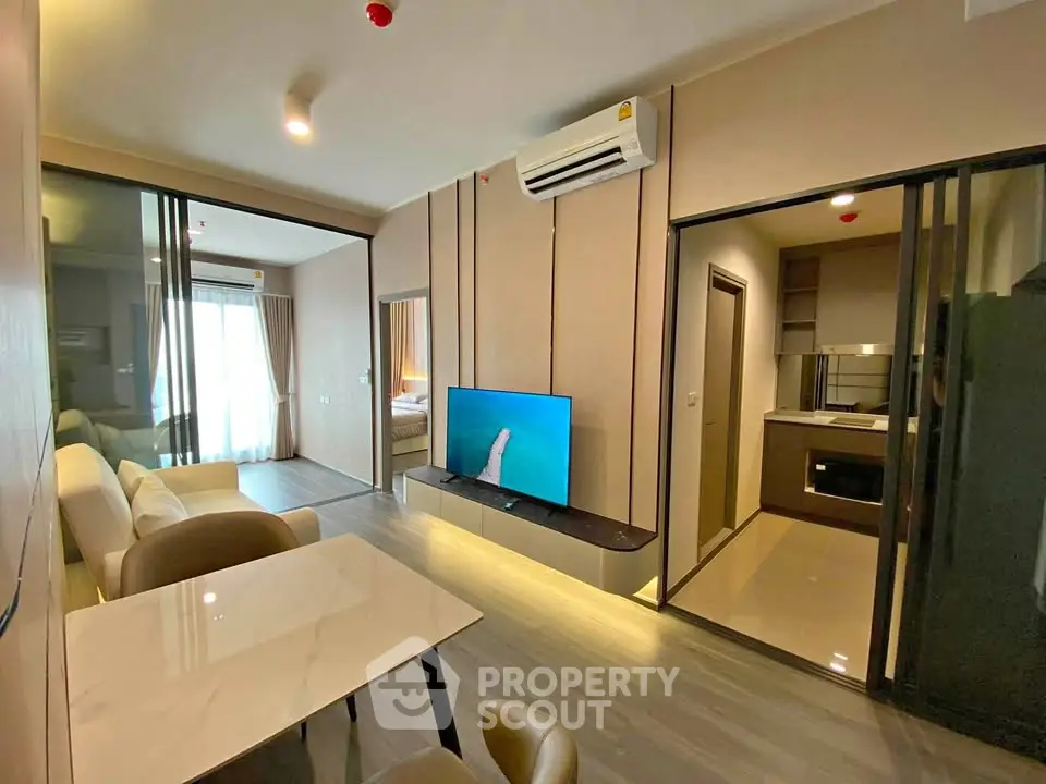Modern apartment interior with open living room, dining area, and kitchen featuring sleek design and natural light.