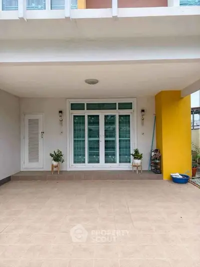 Modern house entrance with clean tiled patio and potted plants