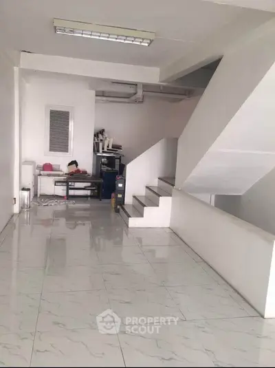 Spacious interior with modern staircase and glossy tiled flooring, ideal for versatile use.
