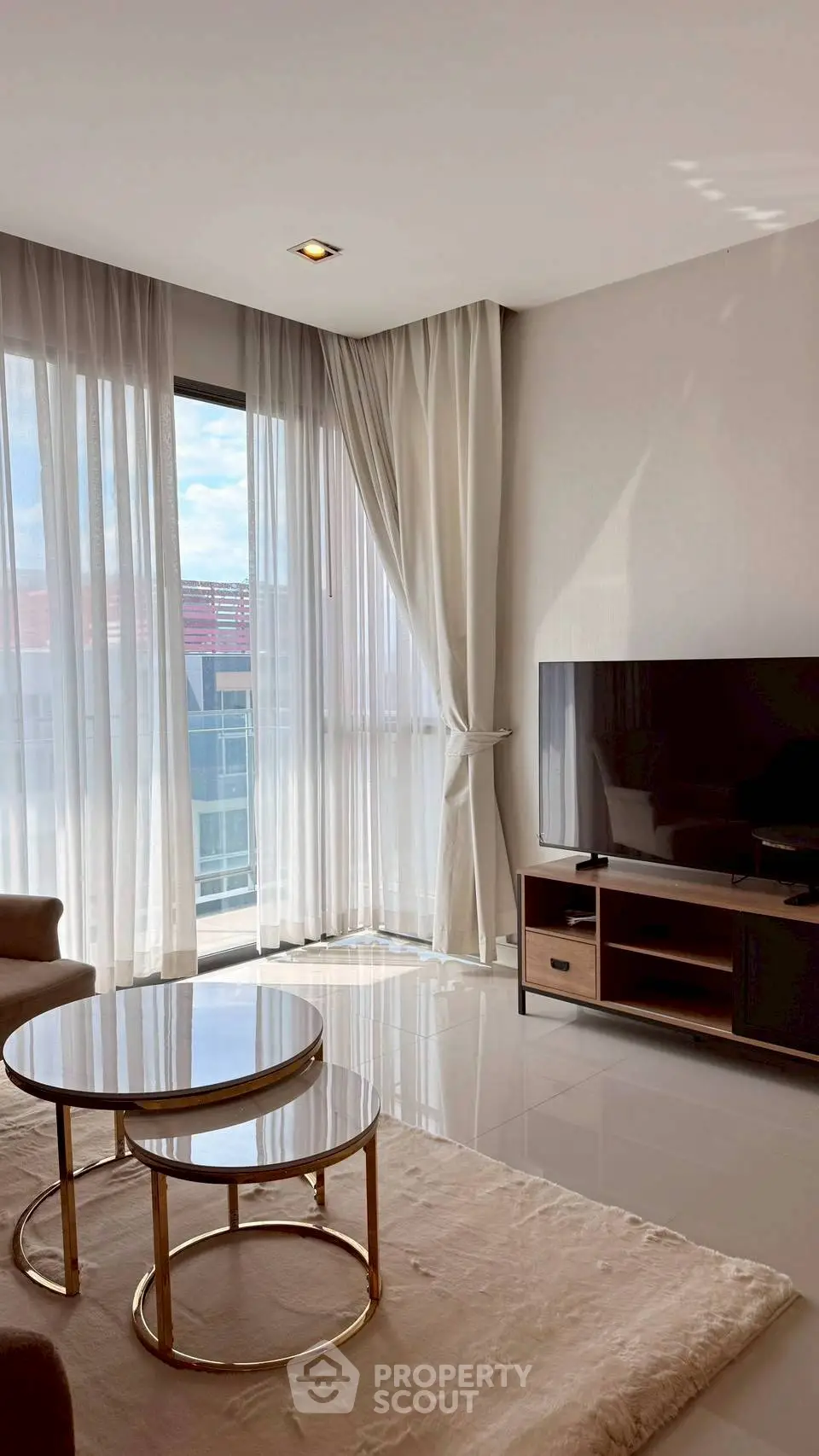 Elegant living room with large windows, modern furniture, and natural light.