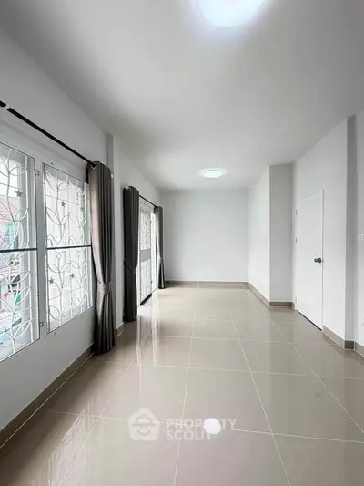 Spacious empty room with large windows and glossy tiled floor, perfect for customization.