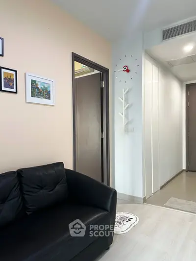 Modern living room with black leather sofa and stylish wall clock, showcasing contemporary interior design.