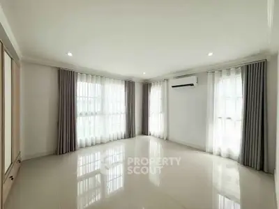 Spacious empty living room with large windows and air conditioning, perfect for customization.