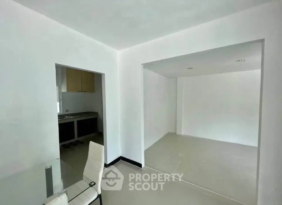 Spacious open-plan living area with modern kitchen in a minimalist apartment.