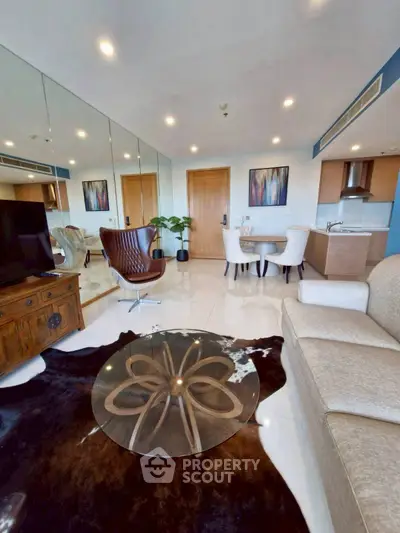 Modern living room with elegant decor, mirrored wall, and open kitchen layout in a stylish apartment.