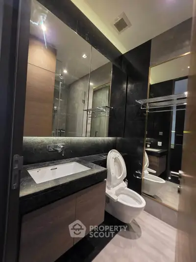 Luxurious modern bathroom with sleek black and wood finishes, featuring a large mirror and elegant fixtures.