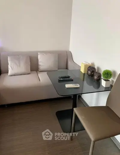 Modern living room with sleek glass table and cozy sofa, perfect for urban living.