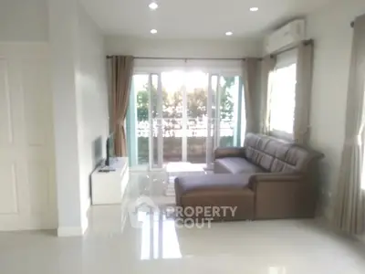 Spacious living room with modern sofa and large windows leading to a balcony, perfect for relaxation.