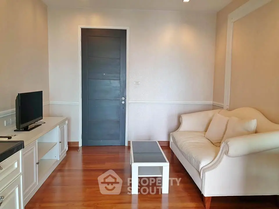 Cozy living room with elegant sofa and modern TV setup on wooden flooring.