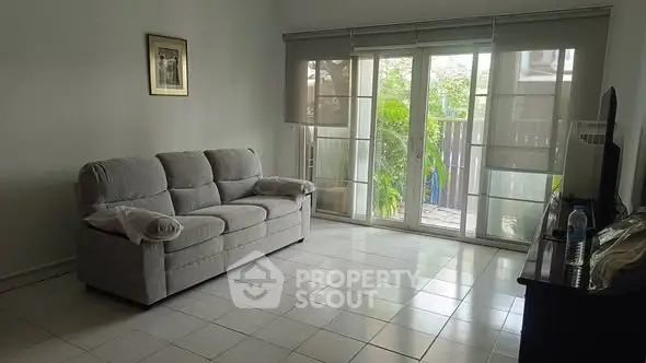 Bright living room with large windows and cozy sofa, perfect for relaxation.