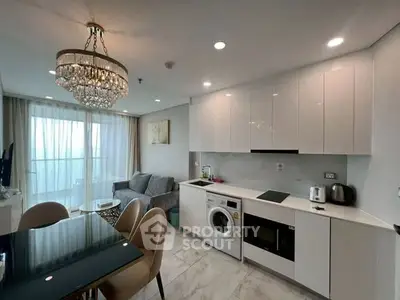 Modern open-layout kitchen and living room with chandelier and balcony view.