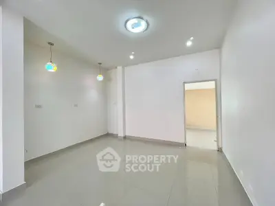 Spacious empty room with modern lighting and tiled flooring, ready for customization.