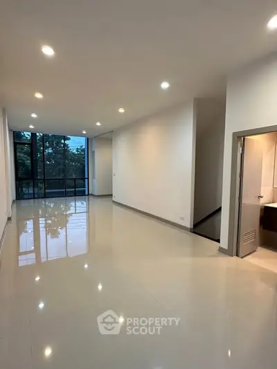 Spacious modern living room with large windows and glossy tile flooring.