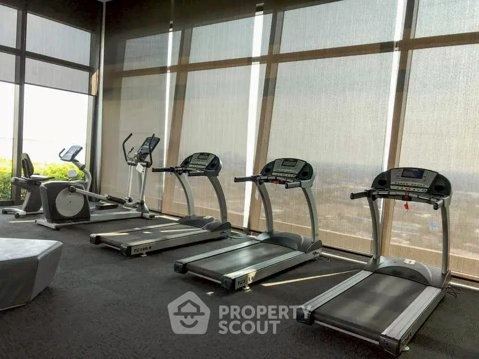 Modern gym with treadmills and exercise bikes in a high-rise building with panoramic views.