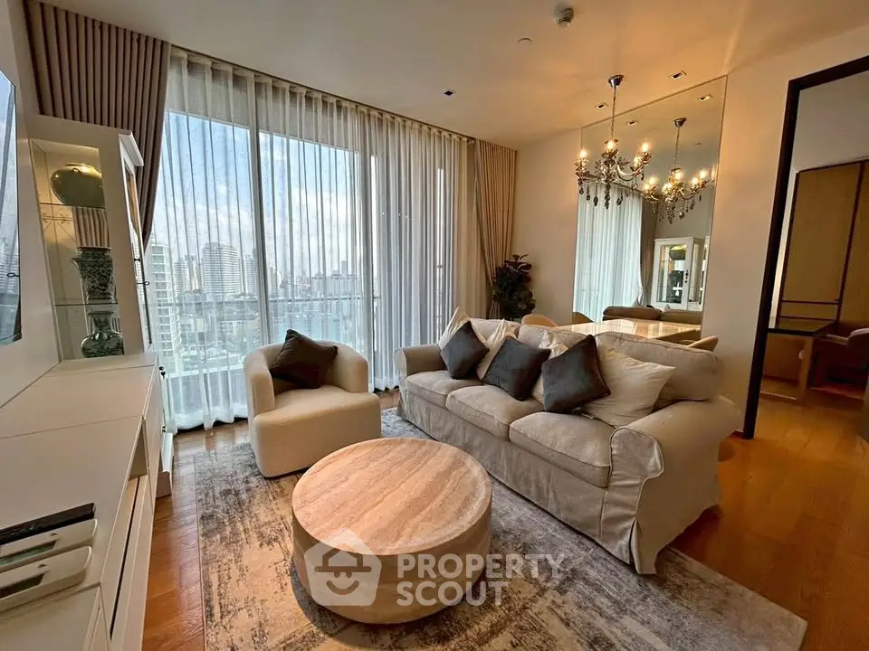 Luxurious living room with elegant decor and city view, featuring plush sofa and modern chandelier.