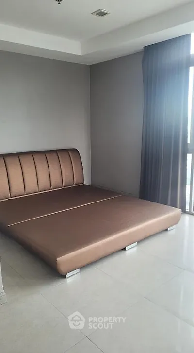 Spacious bedroom with modern bed frame and large window offering natural light.