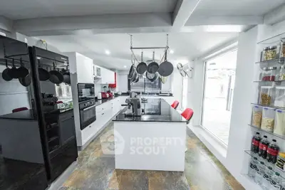 Modern kitchen with sleek black appliances and open layout, featuring a central island and ample natural light.