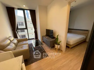 Modern apartment living room with cozy sofa and TV, adjacent to a bedroom with natural light.