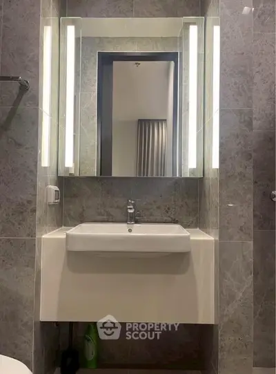 Modern bathroom with sleek vanity and illuminated mirror in luxury apartment.