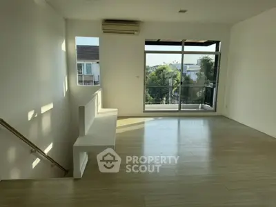 Spacious living room with large windows and balcony view, perfect for natural light lovers.