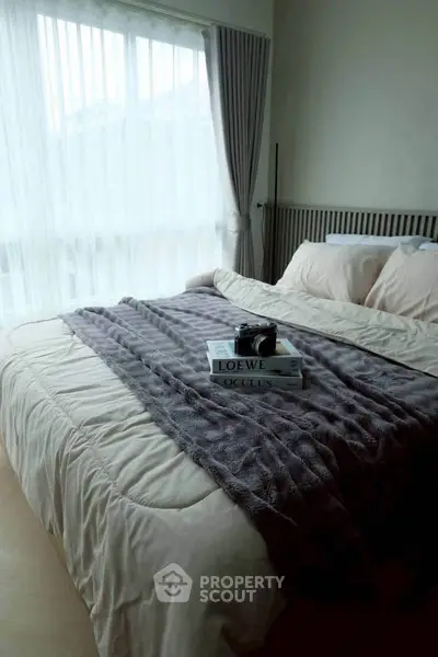 Cozy bedroom with plush bedding and natural light, perfect for relaxation and comfort.