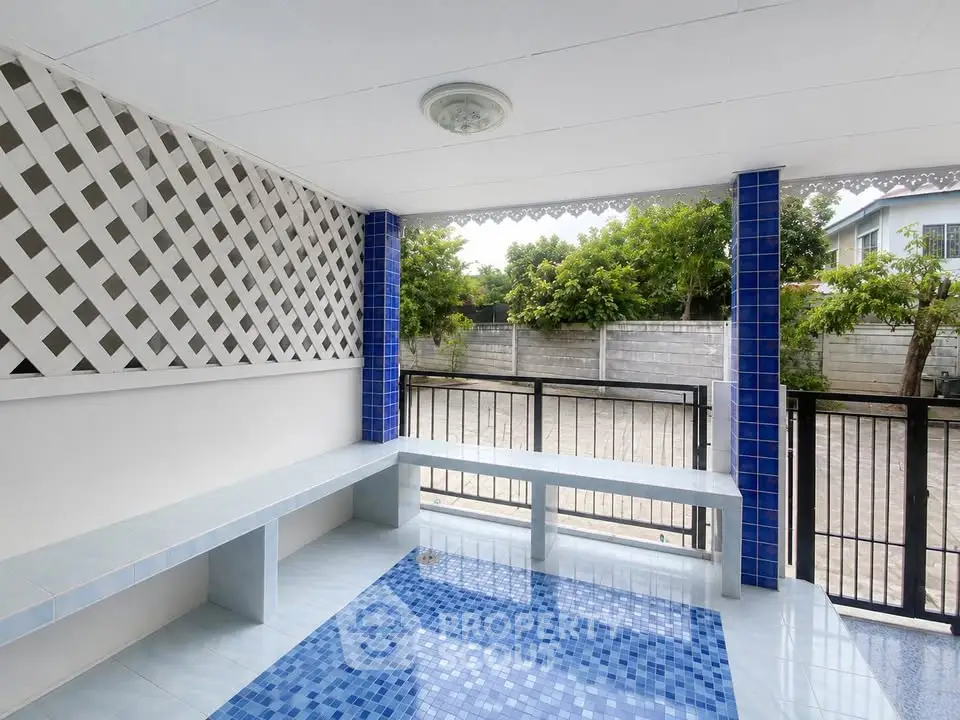 Charming outdoor patio with blue tile accents and garden view, perfect for relaxation and entertaining.