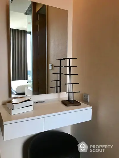 Modern minimalist bedroom with sleek white vanity unit, large mirror, and tasteful decor, offering a serene and stylish personal space.