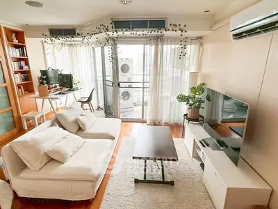 Spacious living room with modern decor and balcony view, featuring cozy seating and entertainment setup.