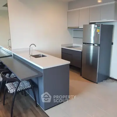 Modern kitchen with sleek design, featuring stainless steel fridge and stylish countertops.