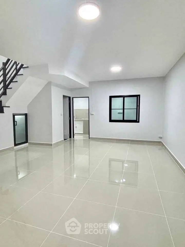 Spacious modern living room with glossy tiled floor and staircase