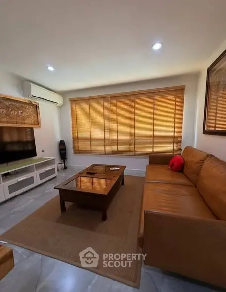 Cozy living room with leather sofa and large window blinds
