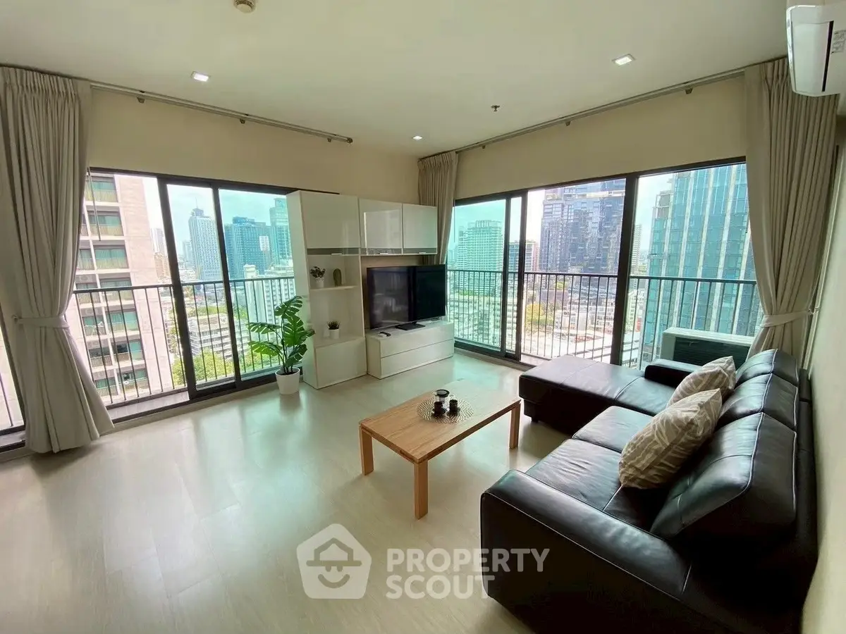 Spacious living room with panoramic city views and modern furnishings.