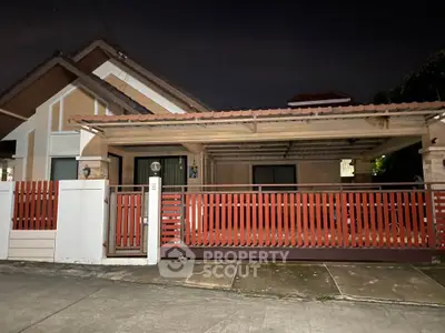 Charming single-story home with red fence and covered carport, perfect for cozy living.