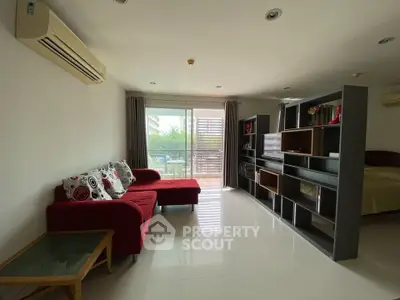 Spacious living room with modern red sofa and large sliding glass doors leading to balcony.