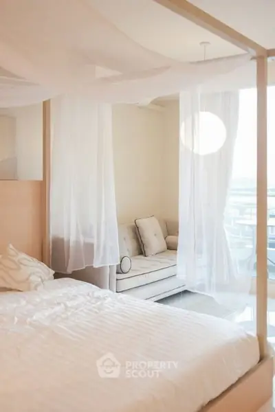 Elegant bedroom with canopy bed and cozy seating area, featuring soft lighting and modern decor.