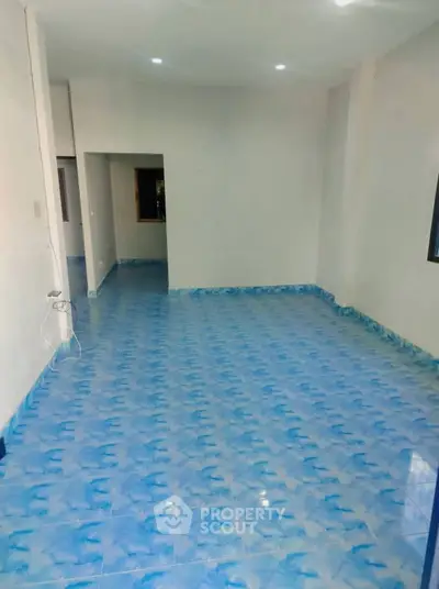 Spacious room with unique blue patterned flooring and white walls, ideal for versatile interior design.