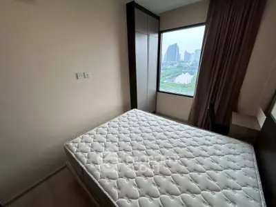 Cozy bedroom with large window offering stunning city view, featuring a comfortable mattress and modern wardrobe.